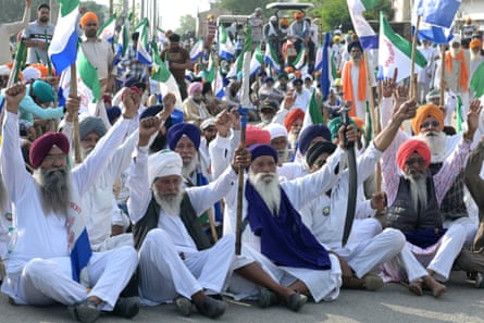 Farmers sit down in a road waving flags