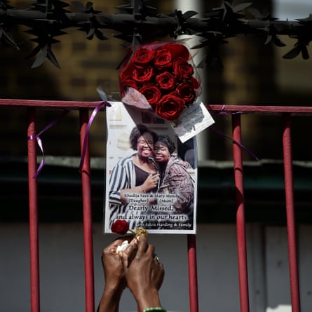 A woman attaches a red rose to a poster of a person missing afte the Grenfell Tower fire in north Kensington