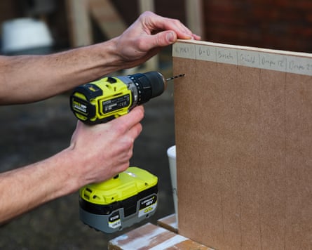 The Ryobi Brushless Combi is being tested by drilling into sheet of MDF which is being held upright by the writer. His arms and hands are in frame.