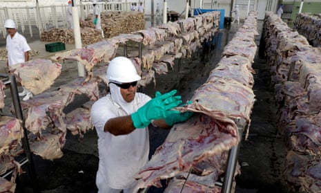 A worker spreads out meat at a JBS plant.