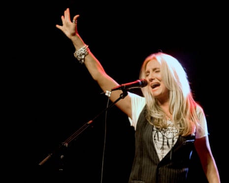 Sass Jordan sings into a microphone on stage, raising one arm upward