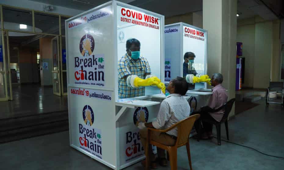 Medical staff test people for coronavirus in kiosks at Ernakulam medical college in Kerala.