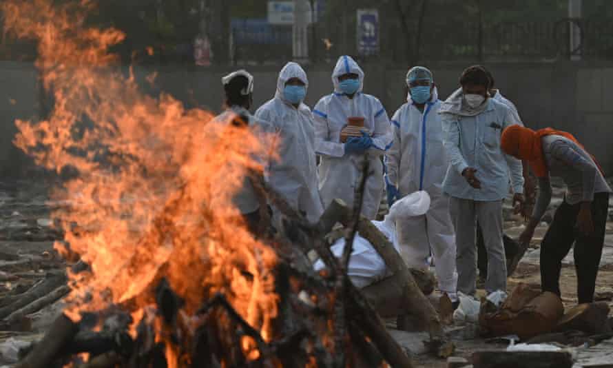 Relatives wearing personal protective equipment (PPE) perform rituals during the cremation of a loved one at a crematorium in New Delhi.