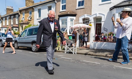 Royal Navy veteran, Charles Medhurst, 95, walks along his street for a victory parade as his neighbours cheer and clap in Greenwich, London.