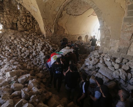 A funeral procession bearing a body wrapped in the Egyptian flag makes it way through a mosque filled with rubble