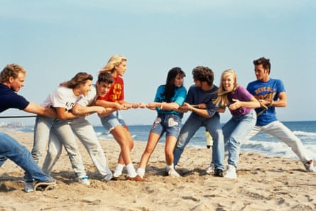 cast play tug of war on a sandy beach