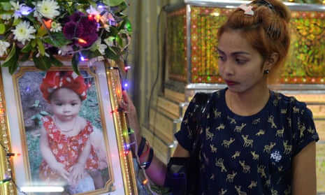 Jiranuch Trirat, mother of the 11-month-old who was killed by her father, stands next to a picture of her daughter at a temple in Phuket.