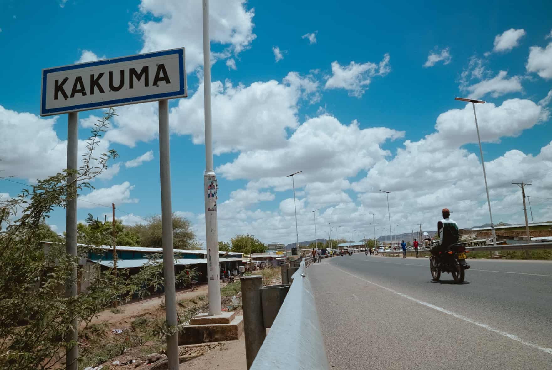 A sign along a road reads ‘Kakuma’ as a motorcyclist goes by.