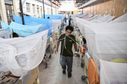 A dengue fever patient walks among beds where others with the disease are resting under mosquito nets at a hospital in northern Peru this year.