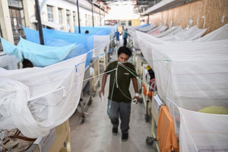 A dengue fever patient walks among patients resting under mosquito nets at a hospital in Sullana, Piura.