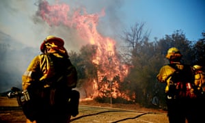 Firefighters battle a blaze in Malibu, California. The Woolsey fire has burned over 70,000 acres and has reached the Pacific Coas.