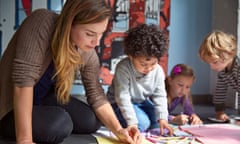 A teacher drawing on paper with young pupils in a preschool class