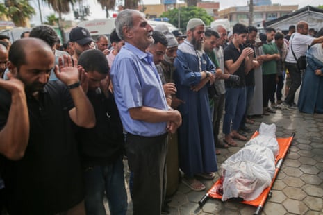 People in in Deir al-Balah pray next to the body of someone killed in an Israeli airstrike, 10 June.