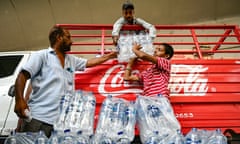 Workers unload water bottles from a truck