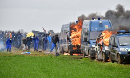 Protesters stand next to French gendarmes’ burning cars during a demonstration in Sainte-Soline on 25 March.