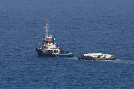 A tugboat tows a barge loaded with humanitarian aid for Gaza, as seen from Larnaca, Cyprus, on Saturday.