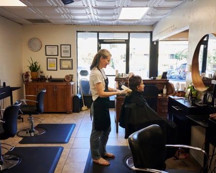 A female grooms nan hairsbreadth of different female sitting successful a salon chair.