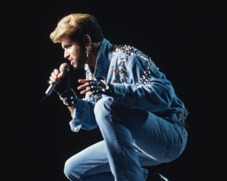 George Michael half kneeling while singing into a microphone