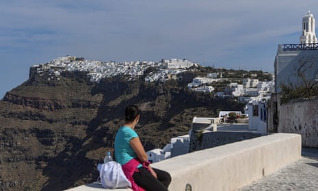 Female holidaymaker gazes at the town of Fira on the Greek island of Santorini in the Aegean Sea.