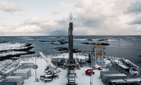Spectrum stands on a launchpad with the icy sea in the background and support vehicles standing by