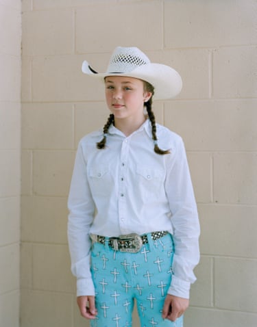 girl in broad brimmed hat, spangly belt and pigtails smiles into camera