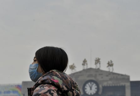 A woman wears a mask in front of Harbin railway station in China