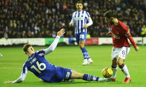 Liam Shaw of Wigan Athletic fouls Bruno Fernandes of Manchester United for a penalty.