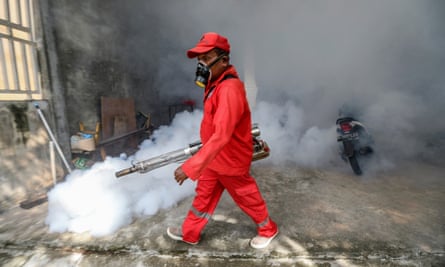 A worker in overalls fumigates a room in Indonesia to tackle the spread of dengue fever