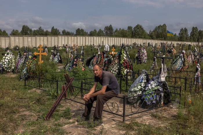 A worker rests during the mass burial of unidentified people who were killed in the Bucha district during the Russian occupation, at a cemetery in Bucha, northwest of Kyiv, Ukraine, on 11 August 2022.