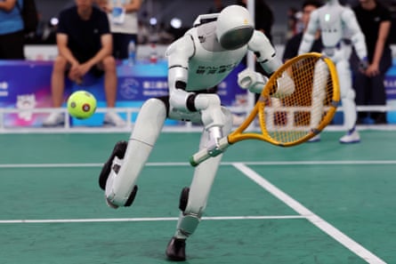 A Galbot humanoid robot dives for the ball during a demonstration of a tennis match with a human player, before the opening ceremony for the second World Humanoid Robot Games, in Beijing