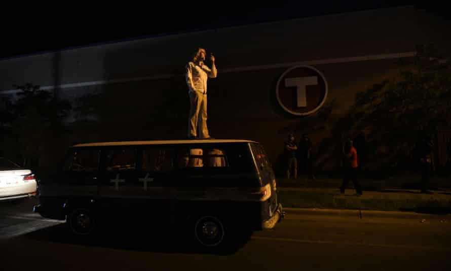 A medic supervises demonstrations from the roof of a makeshift medic van outside the fifth police precinct in Minneapolis