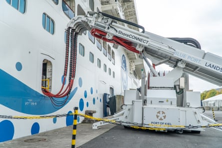 A cruise ship in a port hooked up to a power supply.
