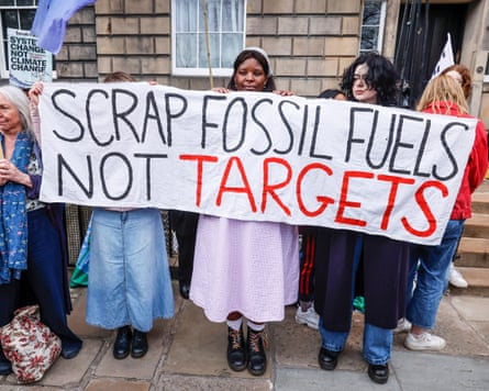 Friends of the Earth campaigners carry a banner that reads ‘scrap fossil fuels, not targets’