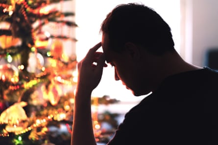 Man looking sad in silhouette by a Christmas tree