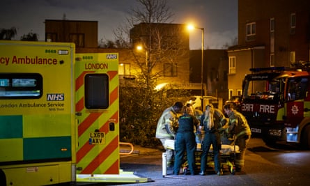 Ambulance workers and fire officers help a casualty on a stretcher