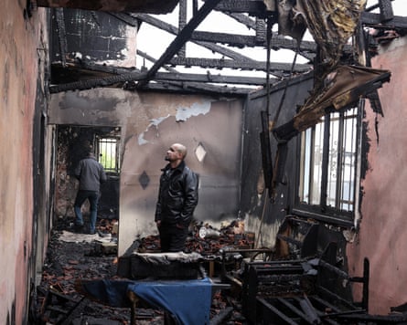 A man standing in a charred and roofless room