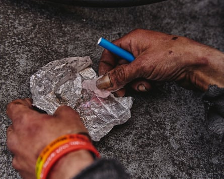 A man holds a piece of aluminum foil and drug paraphernelia.
