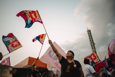 Indigenous leader Joênia Wapichana waves a Lula flag overhead at a rally