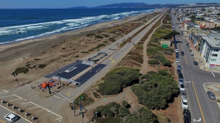 Aerial view of two lanes of closed highway between ocean and residential area.