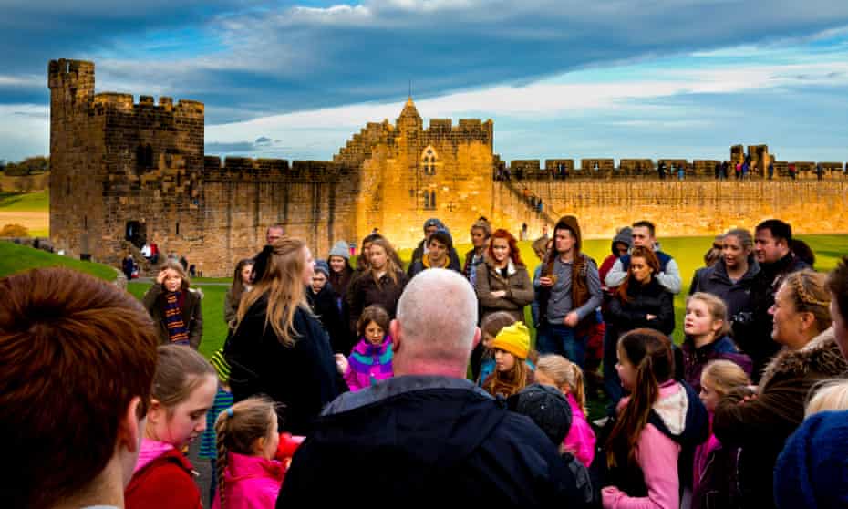 A tour guide with visitors on a Harry Potter theme tour of Alnwick Castle in Northumberland. 