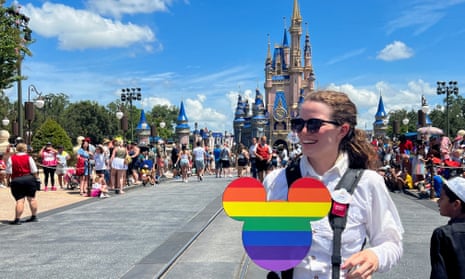 woman at disney world with a rainbow flag mickey mouse head