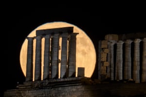 La luna de fresa se eleva en el cielo detrás del antiguo templo de Poseidón en Cabo Sounion, Grecia