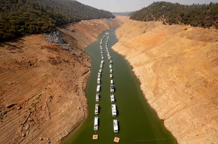 Houseboats sit in a narrow section of water in a depleted Lake Oroville.