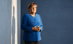 Angela Merkel standing with her hands held together in a signature pose