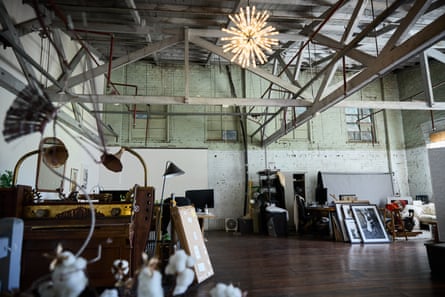 Tortuga Studios’ eclectic interior with exposed beams, a sparkler-style chandelier, and framed artwork leaning against walls