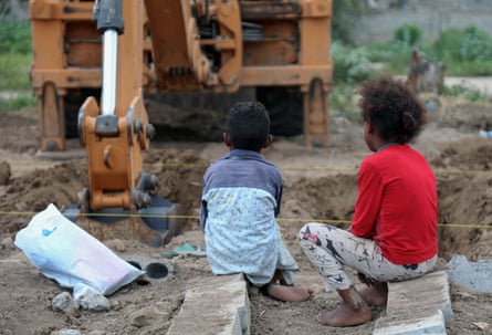 Yemeni children watch as an excavator digs graves at a specific plot for Covid-19 victims, at a cemetery in Taez, on 14 June 2020.