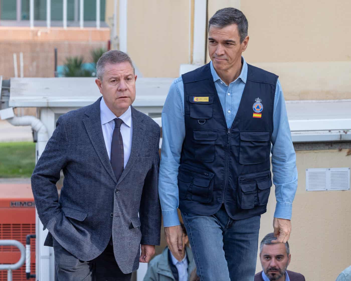 Pedro Sánchez and Emiliano García-Page walk together outdoors near a rescue coordination centre