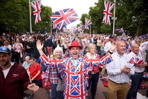 People dressed in union jack themed outfits wave flags, as they gather on the Mall ahead of a concert outside Buckingham Palace
