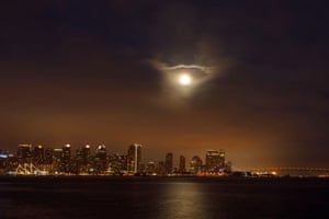 The moon rises through low clouds above the city of San Diego in California, US