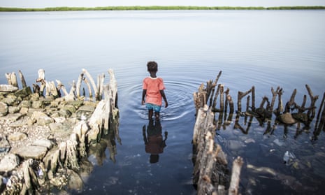 A young girl wades into water where the family kitchen once stood in Diamniadio Island, Saloum Delta in Senegal